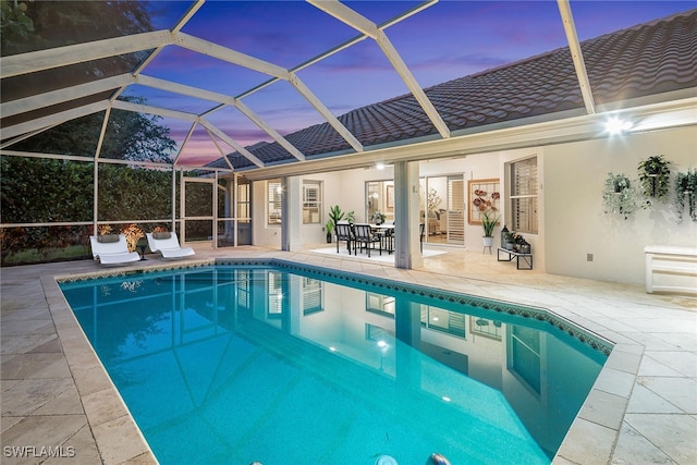 pool at dusk with a lanai and a patio