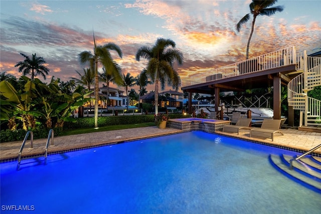 pool at dusk with a patio area and an in ground hot tub