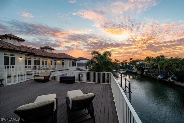 deck at dusk featuring a water view