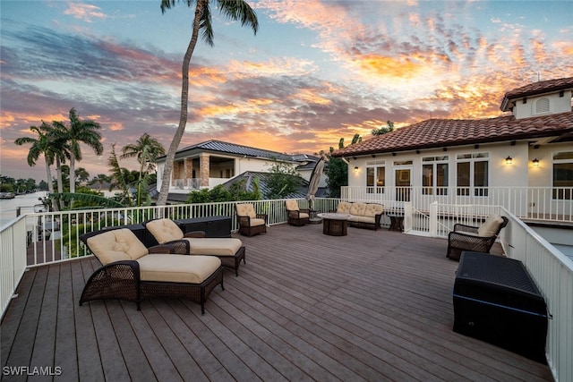 deck at dusk featuring a water view and outdoor lounge area