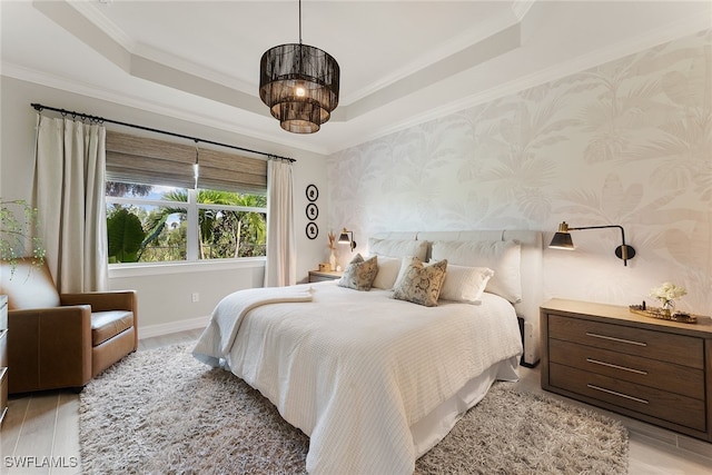 bedroom with ornamental molding, light hardwood / wood-style flooring, and a tray ceiling