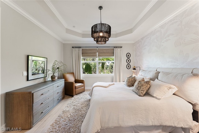 bedroom with light wood-type flooring, a raised ceiling, a notable chandelier, and crown molding