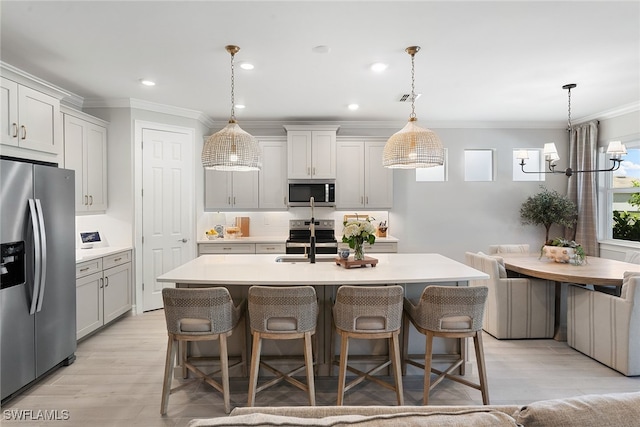 kitchen featuring a kitchen breakfast bar, stainless steel appliances, sink, decorative light fixtures, and a center island with sink