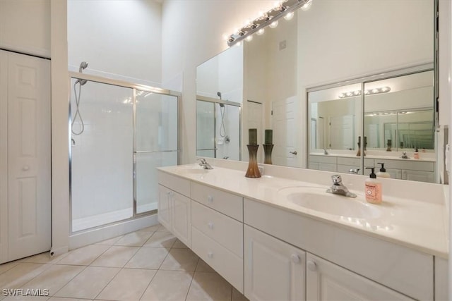 full bathroom featuring double vanity, a stall shower, tile patterned flooring, and a sink