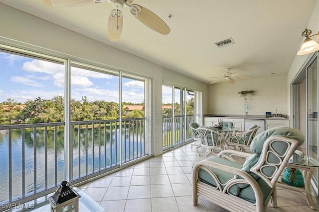 sunroom / solarium with a water view, ceiling fan, and sink