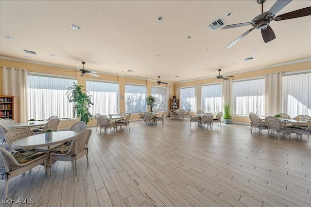 interior space featuring ornamental molding, plenty of natural light, wood finished floors, and visible vents