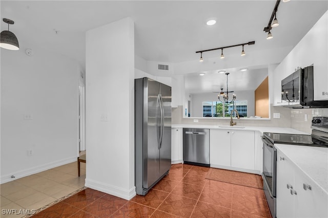 kitchen with stainless steel appliances, hanging light fixtures, dark tile patterned floors, and white cabinetry