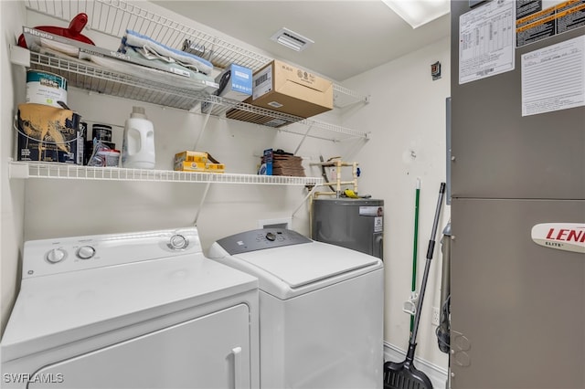 laundry room featuring electric water heater, heating unit, and washer and dryer