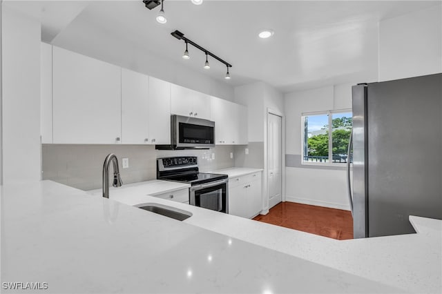 kitchen with appliances with stainless steel finishes, backsplash, sink, and white cabinets