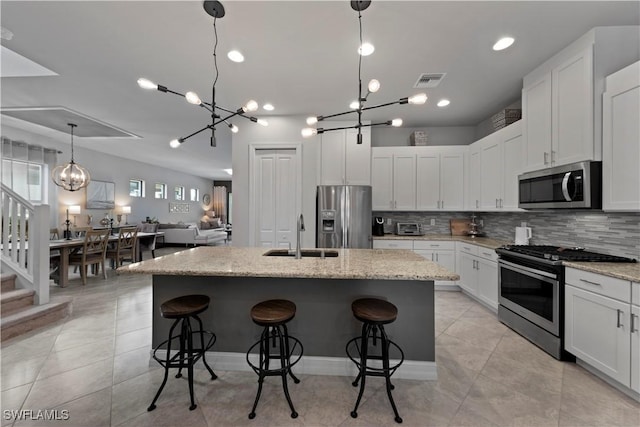 kitchen with white cabinetry, light stone countertops, sink, an island with sink, and appliances with stainless steel finishes