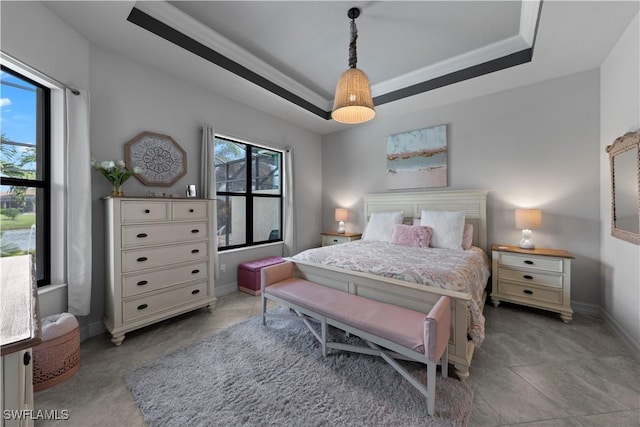 bedroom with a raised ceiling, crown molding, and multiple windows