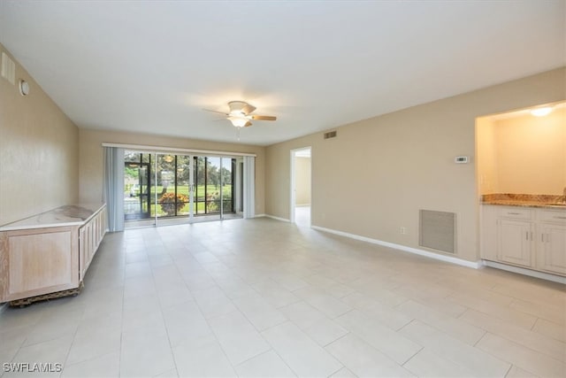 unfurnished living room with ceiling fan, light tile patterned floors, and sink