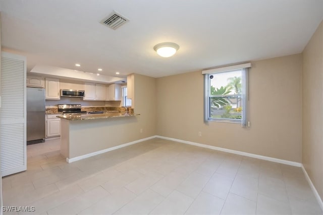 kitchen with light tile patterned floors, sink, kitchen peninsula, appliances with stainless steel finishes, and dark stone counters