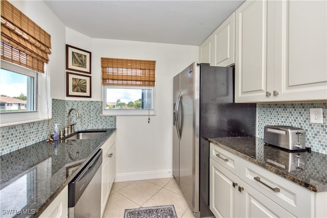 kitchen with sink, stainless steel dishwasher, dark stone counters, decorative backsplash, and white cabinets