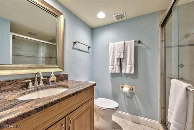 bathroom with tile patterned flooring, vanity, toilet, and an enclosed shower