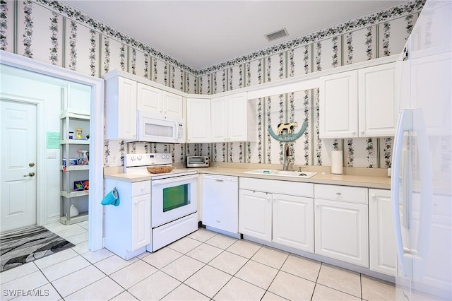 kitchen with light tile patterned flooring, sink, white appliances, and white cabinetry