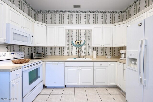 kitchen featuring white appliances, light tile patterned flooring, sink, and white cabinets