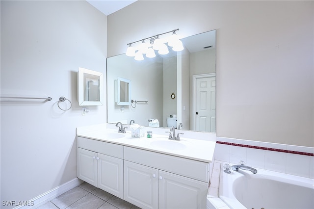 bathroom featuring tile patterned flooring, tiled bath, vanity, and toilet