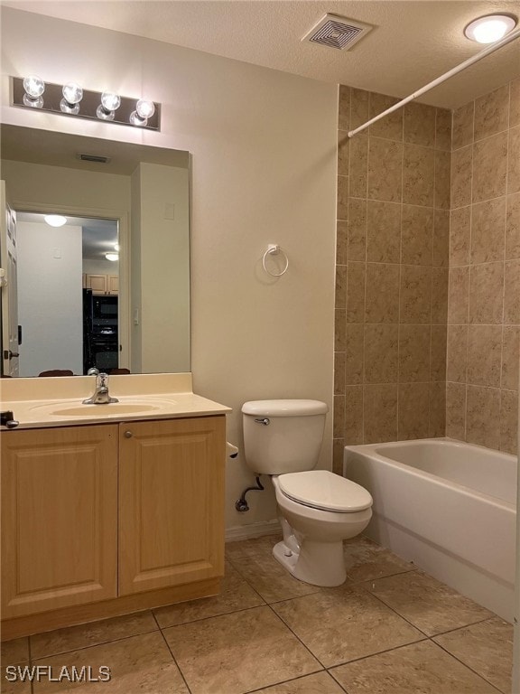 full bathroom with toilet, tile patterned floors, tiled shower / bath, vanity, and a textured ceiling