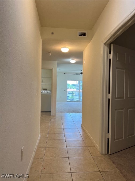 hall featuring washer / clothes dryer and light tile patterned flooring