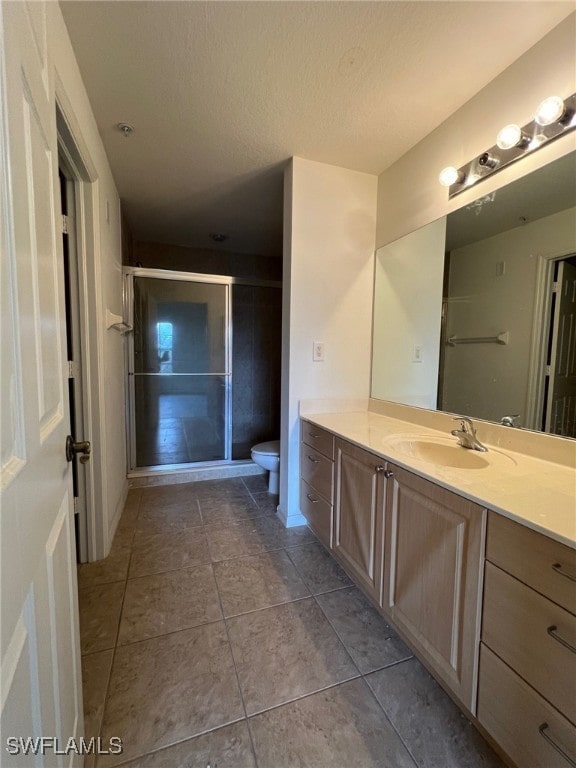 bathroom with vanity, toilet, tile patterned floors, and a shower with door