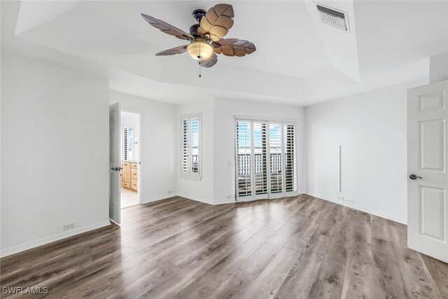 spare room featuring ceiling fan, wood-type flooring, and a raised ceiling