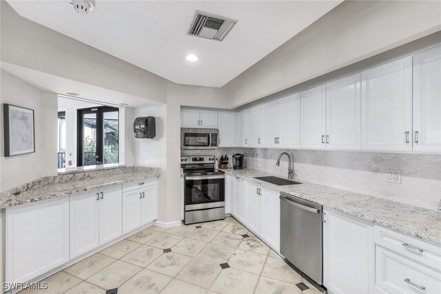 kitchen with sink, appliances with stainless steel finishes, backsplash, light stone counters, and white cabinets