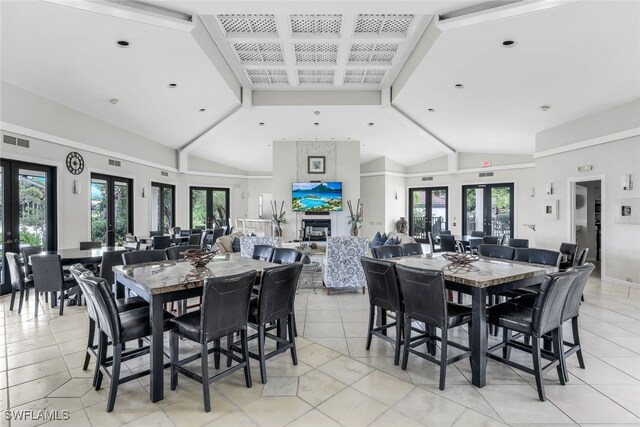 dining space with lofted ceiling, a fireplace, a wealth of natural light, and french doors