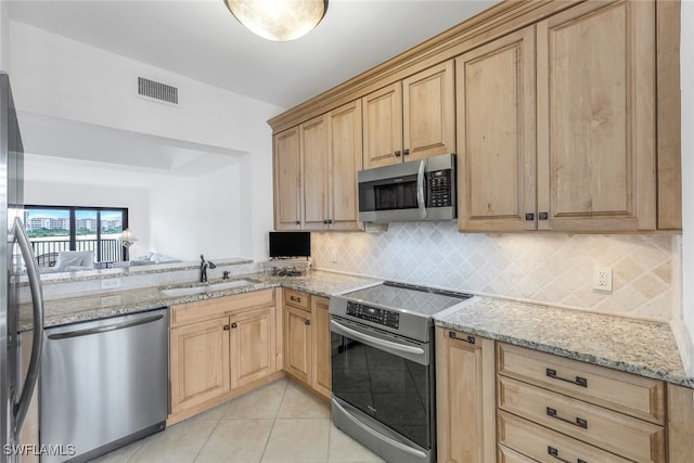 kitchen featuring tasteful backsplash, sink, light tile patterned floors, light stone counters, and stainless steel appliances