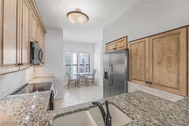 kitchen featuring sink, backsplash, light stone counters, stainless steel refrigerator with ice dispenser, and electric stove