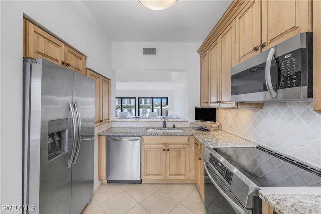 kitchen with light tile patterned flooring, sink, light brown cabinets, stainless steel appliances, and decorative backsplash