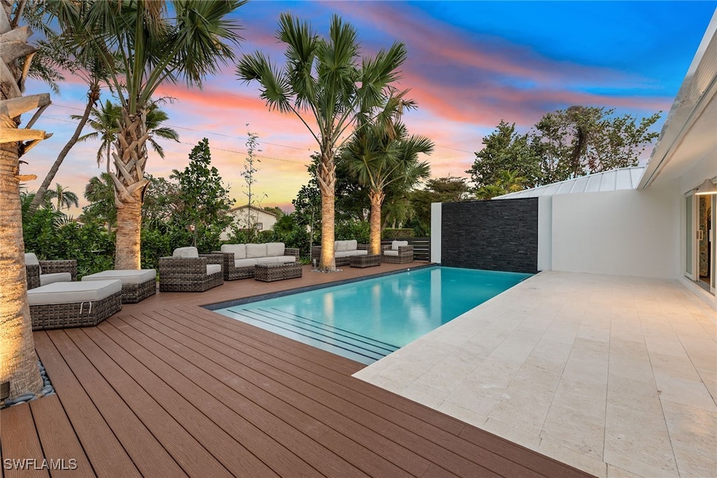 pool at dusk featuring an outdoor living space and a deck