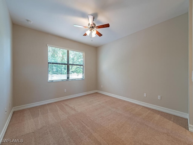 empty room featuring light carpet, a ceiling fan, and baseboards