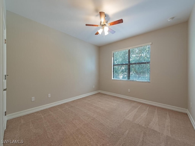 empty room featuring light carpet, baseboards, and ceiling fan