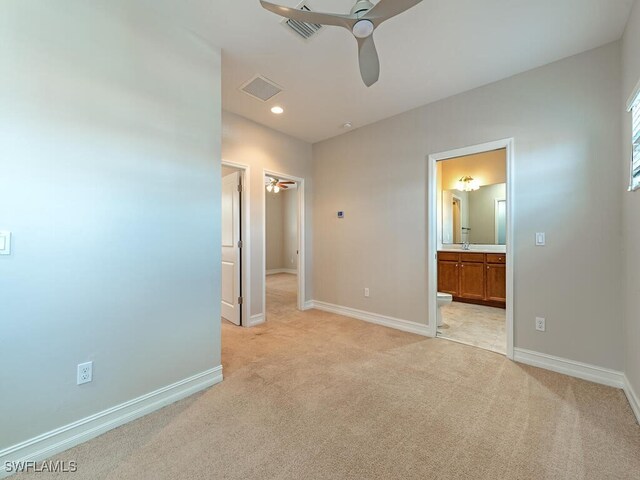 unfurnished bedroom with ensuite bathroom, light colored carpet, and ceiling fan