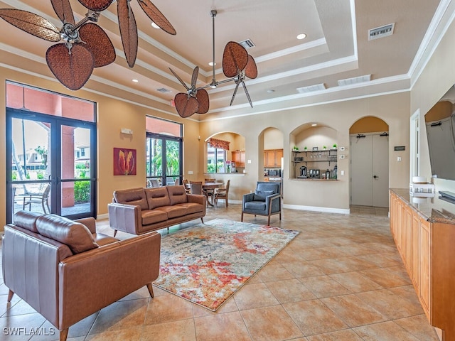 living area with arched walkways, a raised ceiling, visible vents, and crown molding