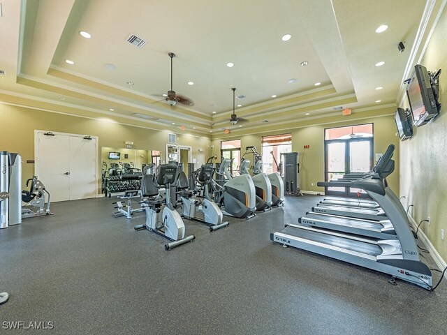 exercise room featuring ceiling fan, a raised ceiling, and ornamental molding