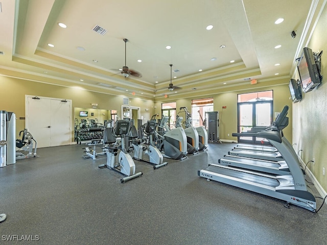 exercise room featuring a tray ceiling, visible vents, ornamental molding, and ceiling fan