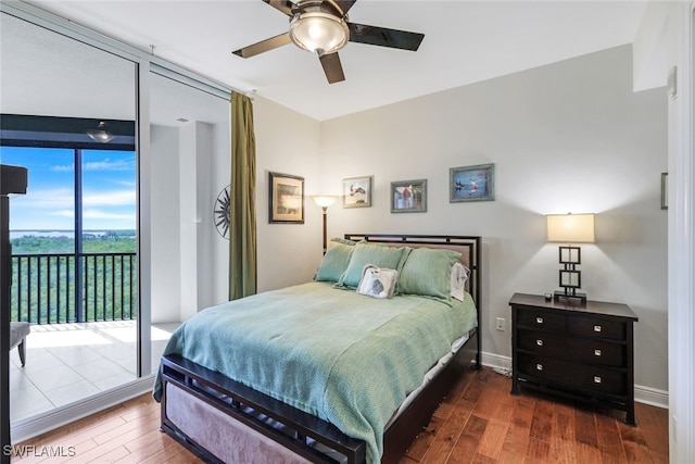 bedroom with ceiling fan, dark hardwood / wood-style floors, access to exterior, and a wall of windows