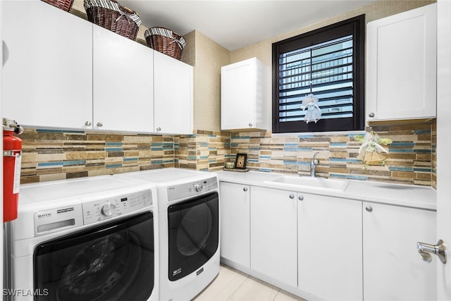 clothes washing area with cabinets, washer and dryer, and sink