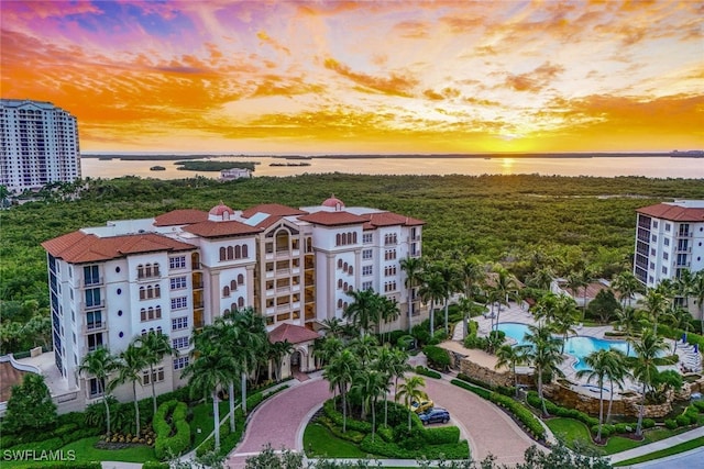 aerial view at dusk featuring a water view