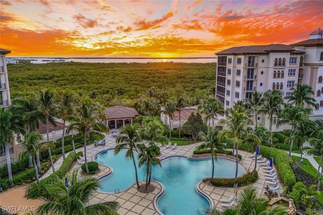 pool at dusk with a patio area