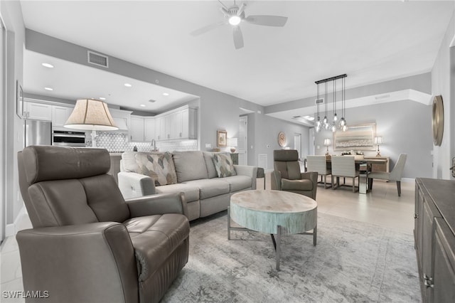 tiled living room featuring ceiling fan with notable chandelier