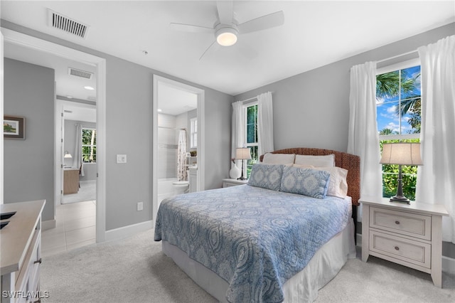 carpeted bedroom with multiple windows, ensuite bath, and ceiling fan