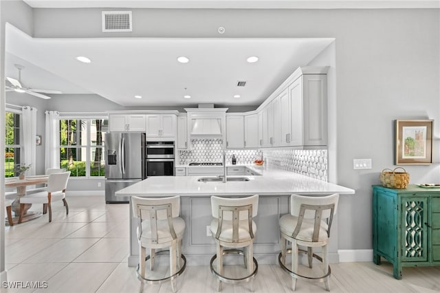 kitchen featuring a breakfast bar, white cabinetry, kitchen peninsula, stainless steel appliances, and ceiling fan