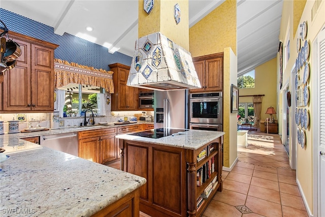 kitchen with light stone counters, light tile patterned floors, sink, a kitchen island, and stainless steel appliances