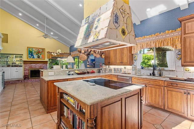 kitchen with a brick fireplace, a center island, ceiling fan, vaulted ceiling with beams, and sink