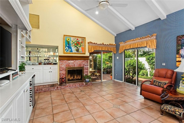 living room with high vaulted ceiling, beamed ceiling, a brick fireplace, ceiling fan, and light tile patterned floors