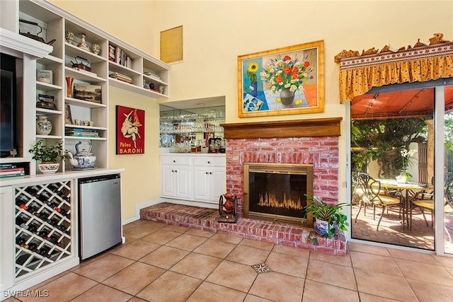 interior space featuring stainless steel fridge, light tile patterned floors, and a brick fireplace