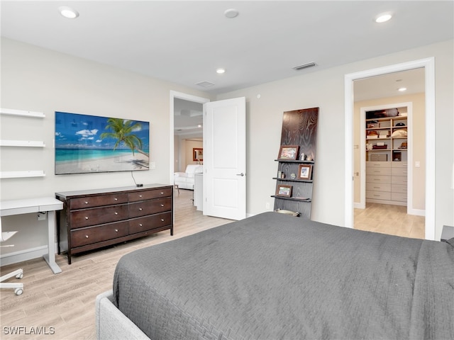 bedroom with light wood-type flooring and a walk in closet